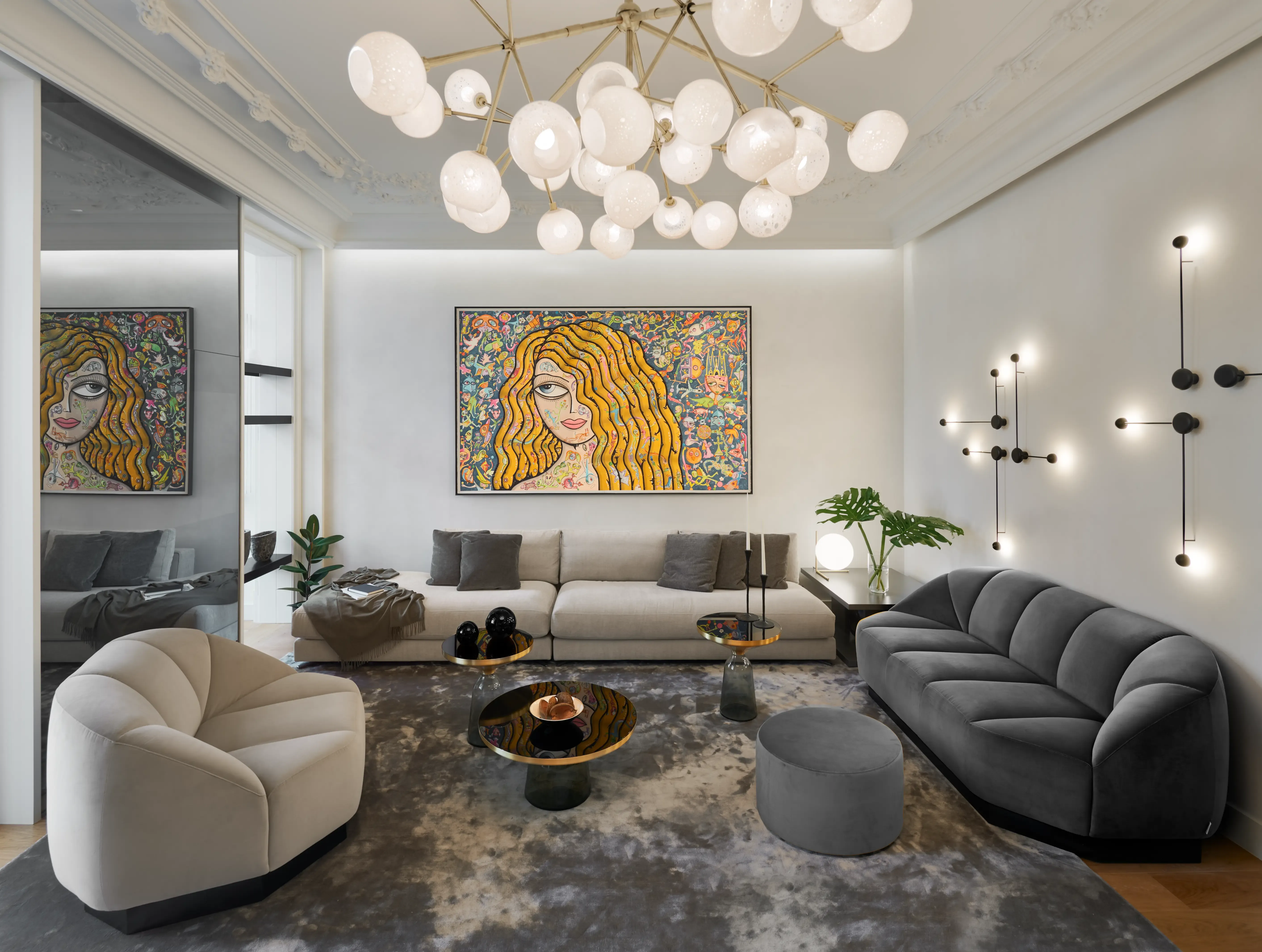 Elegant living room with modern sofas, bold artwork, designer chandelier, and wall lighting, creating a luxurious and artistic interior design.