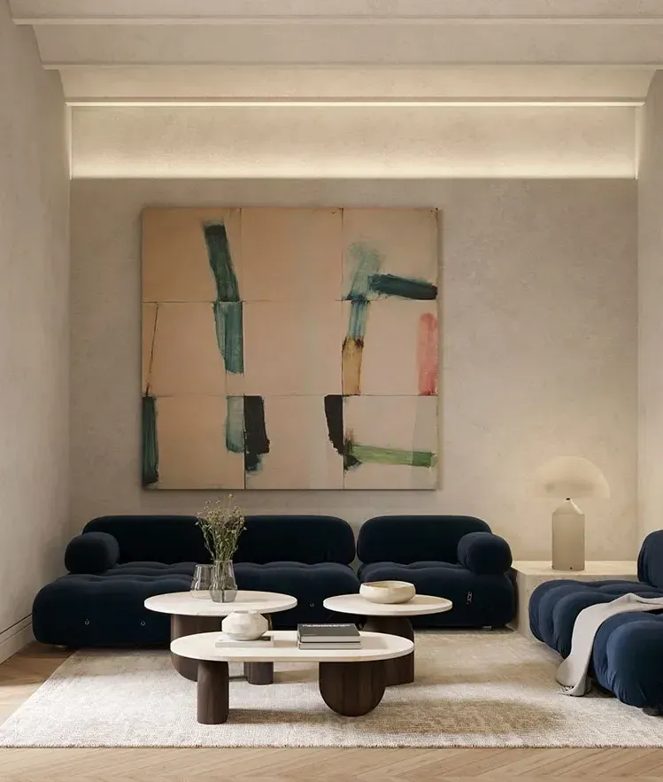 Contemporary living room with navy velvet sofas, abstract artwork, and soft natural lighting in a refined setting.