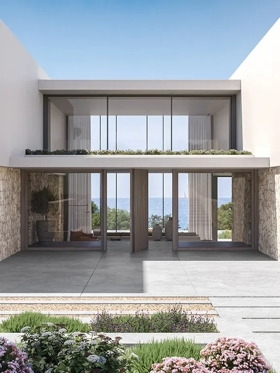 Detail of the villa’s entrance showcasing symmetrical glass doors, sleek facade lines, and ocean view beyond.