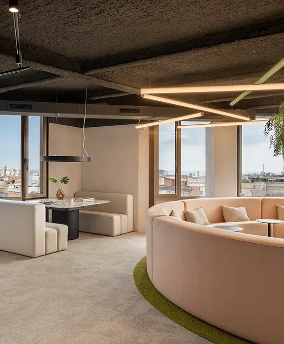 Workspace with meeting booths and a circular lounge under architectural ceiling lights, by LUV Studio.