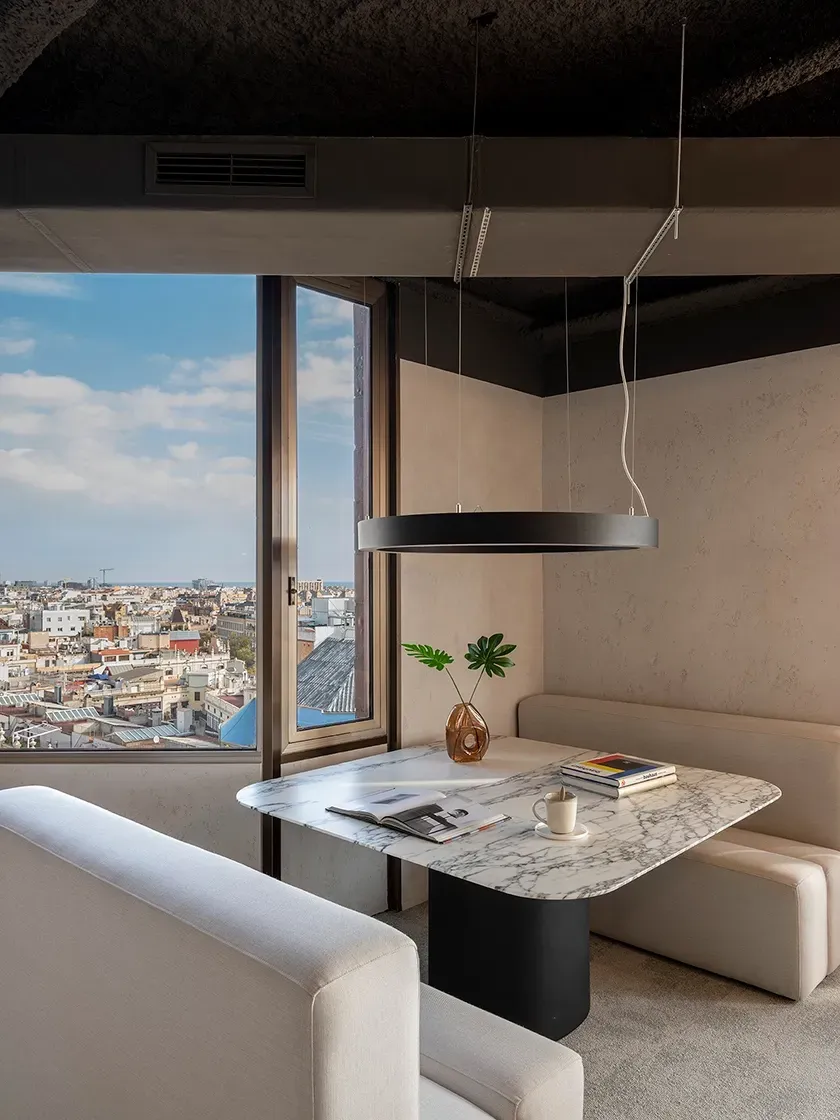 Private corner meeting space with panoramic city views and marble table at LUV Studio's Urquinaona Office