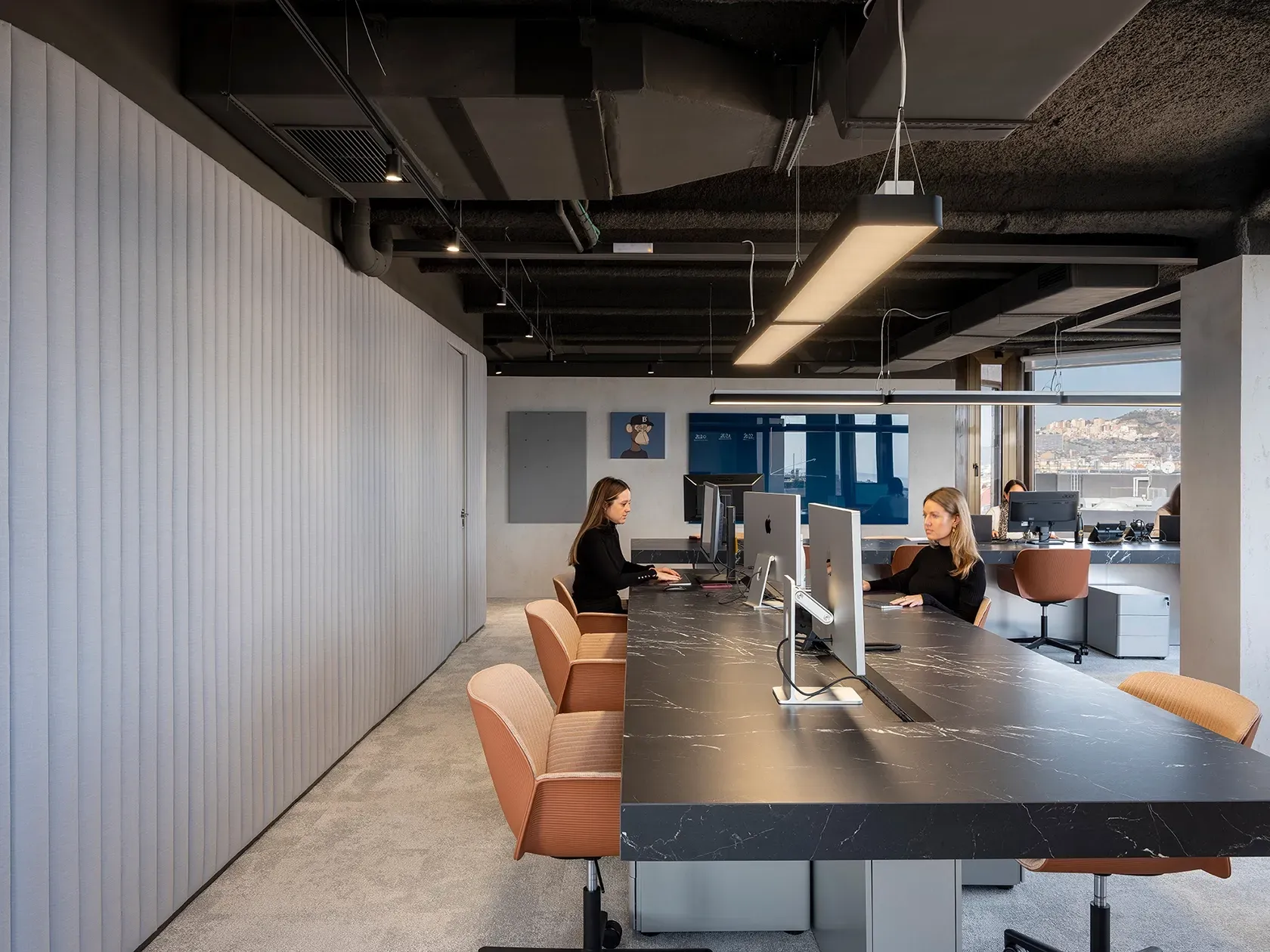 Minimalist open workspace with black desks, neutral tones and views over Barcelona at LUV Studio