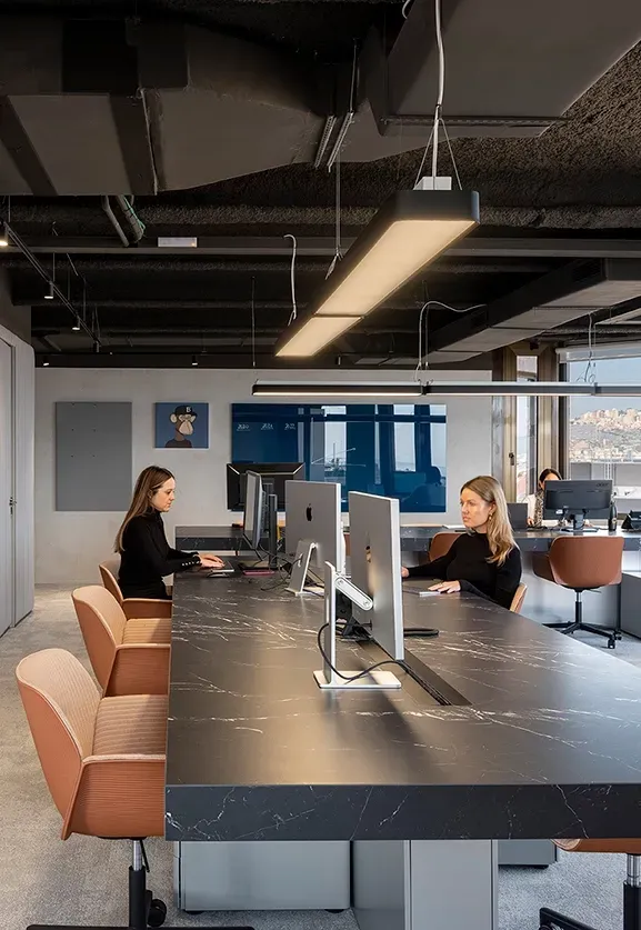 Minimalist open workspace with black desks, neutral tones and views over Barcelona at LUV Studio