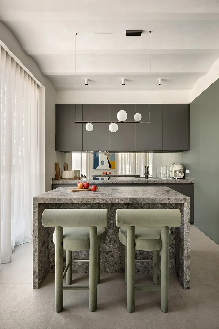 Contemporary kitchen with full-height dark cabinetry, stone worktop and linear suspension light over island seating.