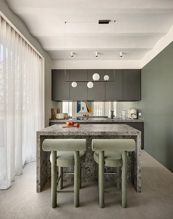 Contemporary kitchen with full-height dark cabinetry, stone worktop and linear suspension light over island seating.