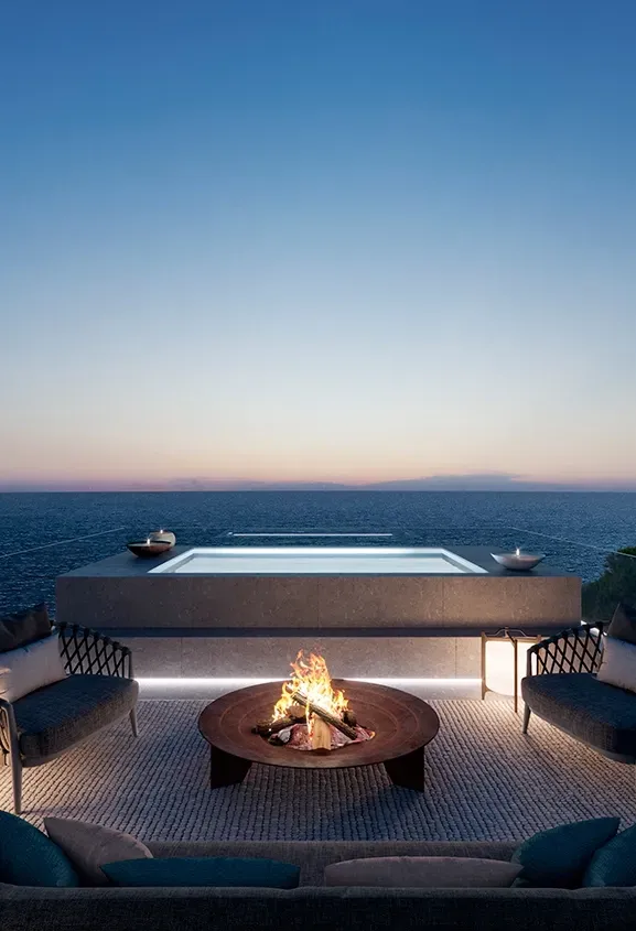 Rooftop terrace with jacuzzi and firepit overlooking the sea at sunset.