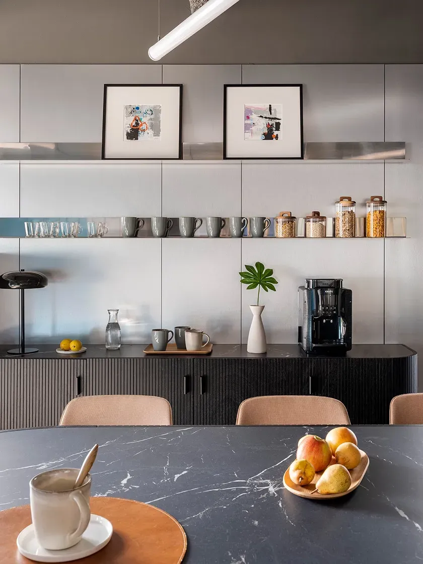 Detail of kitchen space with black countertop, coffee station and curated decor at LUV Studio's office