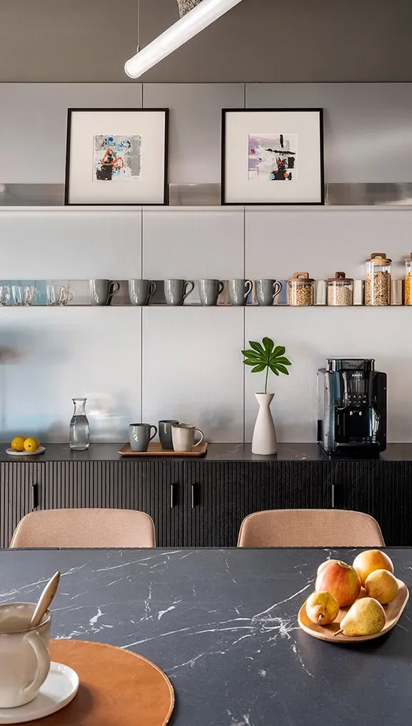 Detail of kitchen space with black countertop, coffee station and curated decor at LUV Studio's office