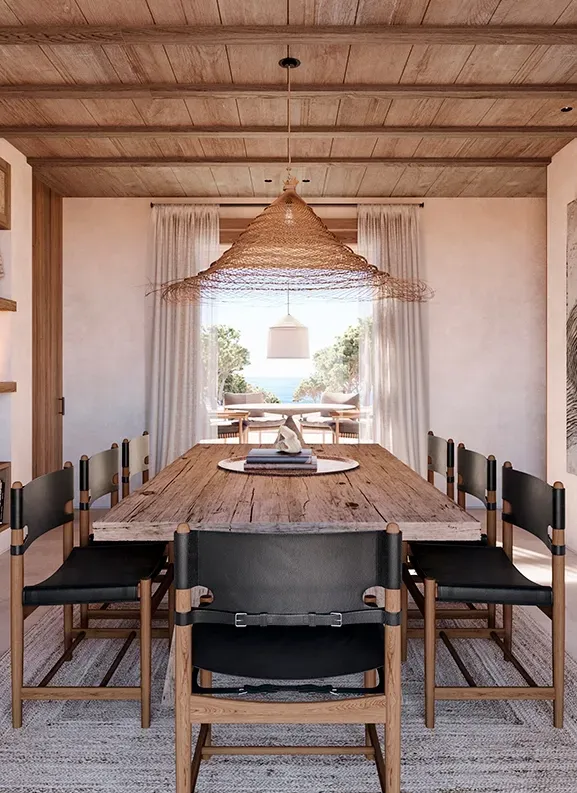 Rustic dining space with a raw wooden table, black leather chairs, and sea views, created by LUV Studio.