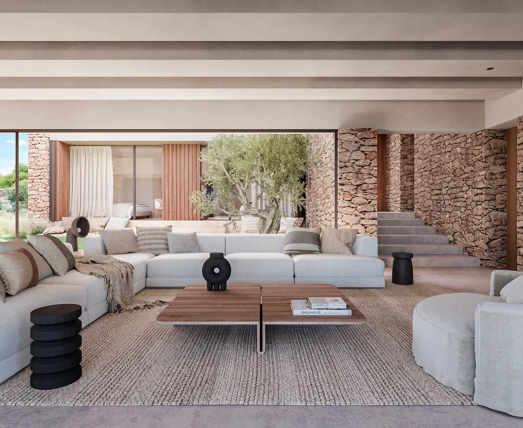 Bright living room with neutral tones and stone walls, overlooking the inner courtyard and olive tree.