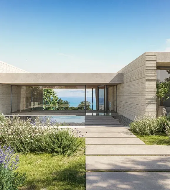 Minimalist luxury entrance path framed by greenery, leading to a modern architectural villa with sea views.
