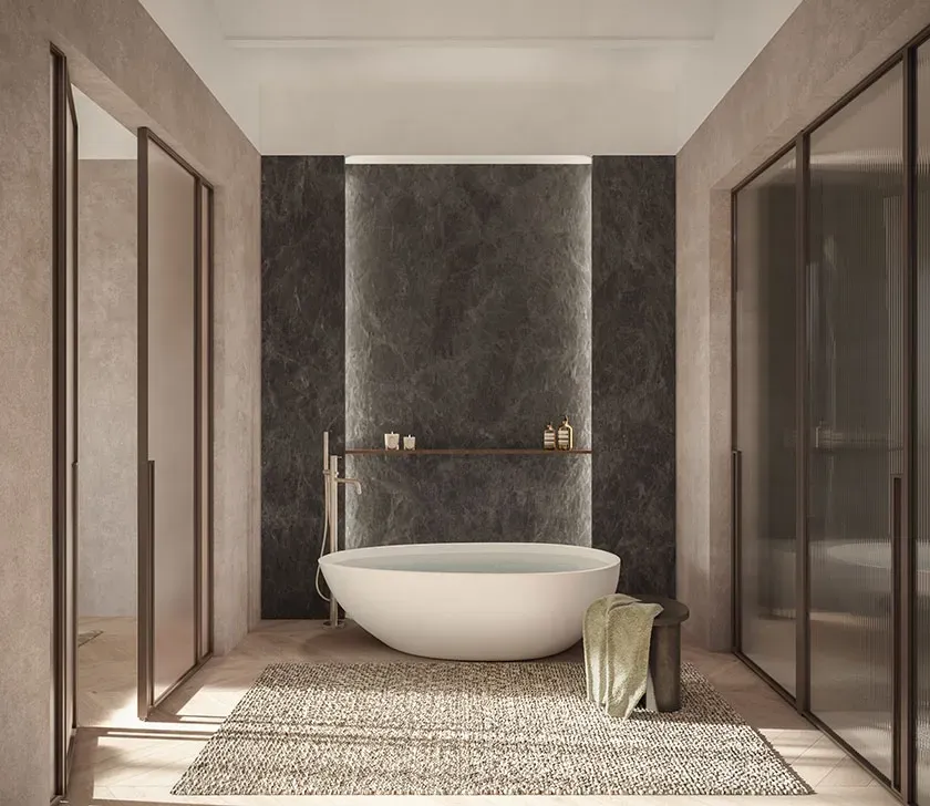 Freestanding bathtub set against a dark marble wall in a luxury bathroom with soft architectural lighting.
