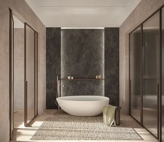 Freestanding bathtub set against a dark marble wall in a luxury bathroom with soft architectural lighting.