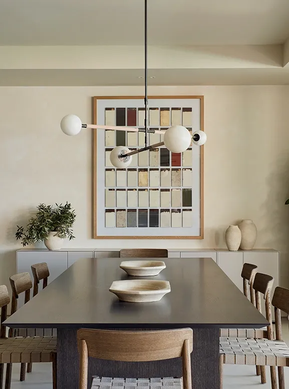 Dining room with wooden table, woven chairs, and modern pendant lamp, blending natural materials in a Mediterranean retreat