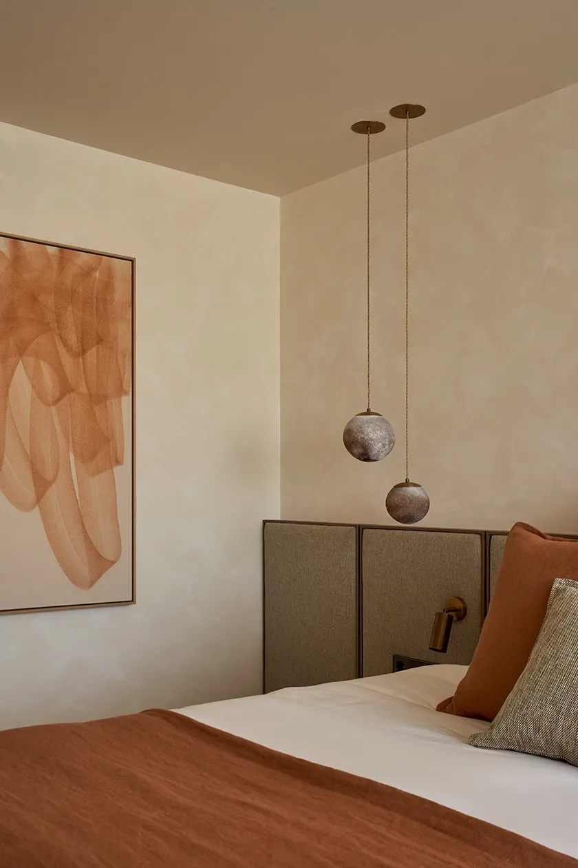 Master bedroom with earthy palette, linen bedding, and contemporary lighting for a serene Mediterranean atmosphere