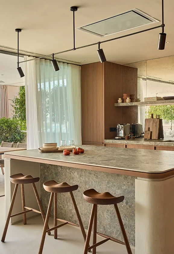 Open kitchen and terrace with stone island, wooden stools, and panoramic sea views in Ibiza residence