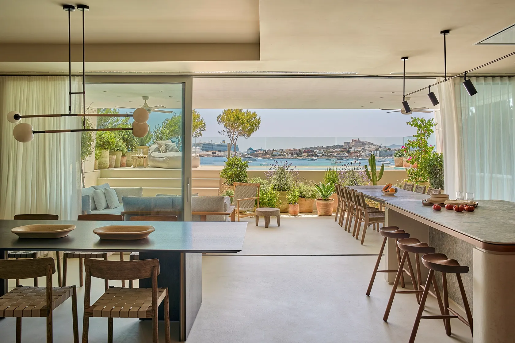 Lush Mediterranean plants and wooden dining table with sea views from Ibiza residence terrace