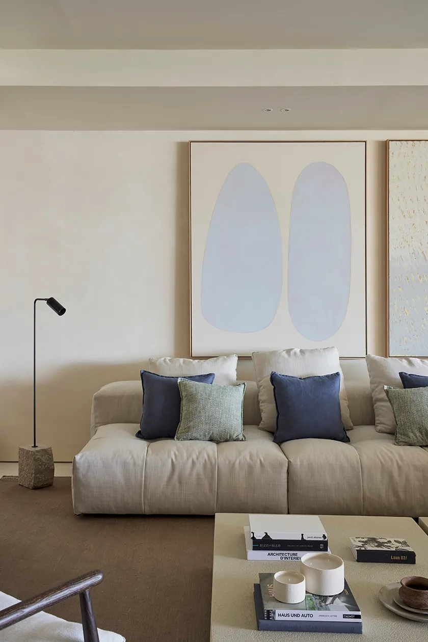 Mediterranean living room in Ibiza residence with modular sofa, neutral tones, and abstract artwork conveying calm and sophistication