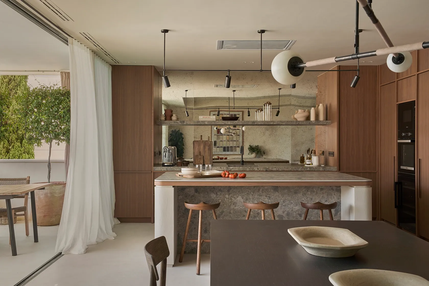 Open kitchen layout with natural stone finishes, wood cabinetry, and contemporary Mediterranean design
