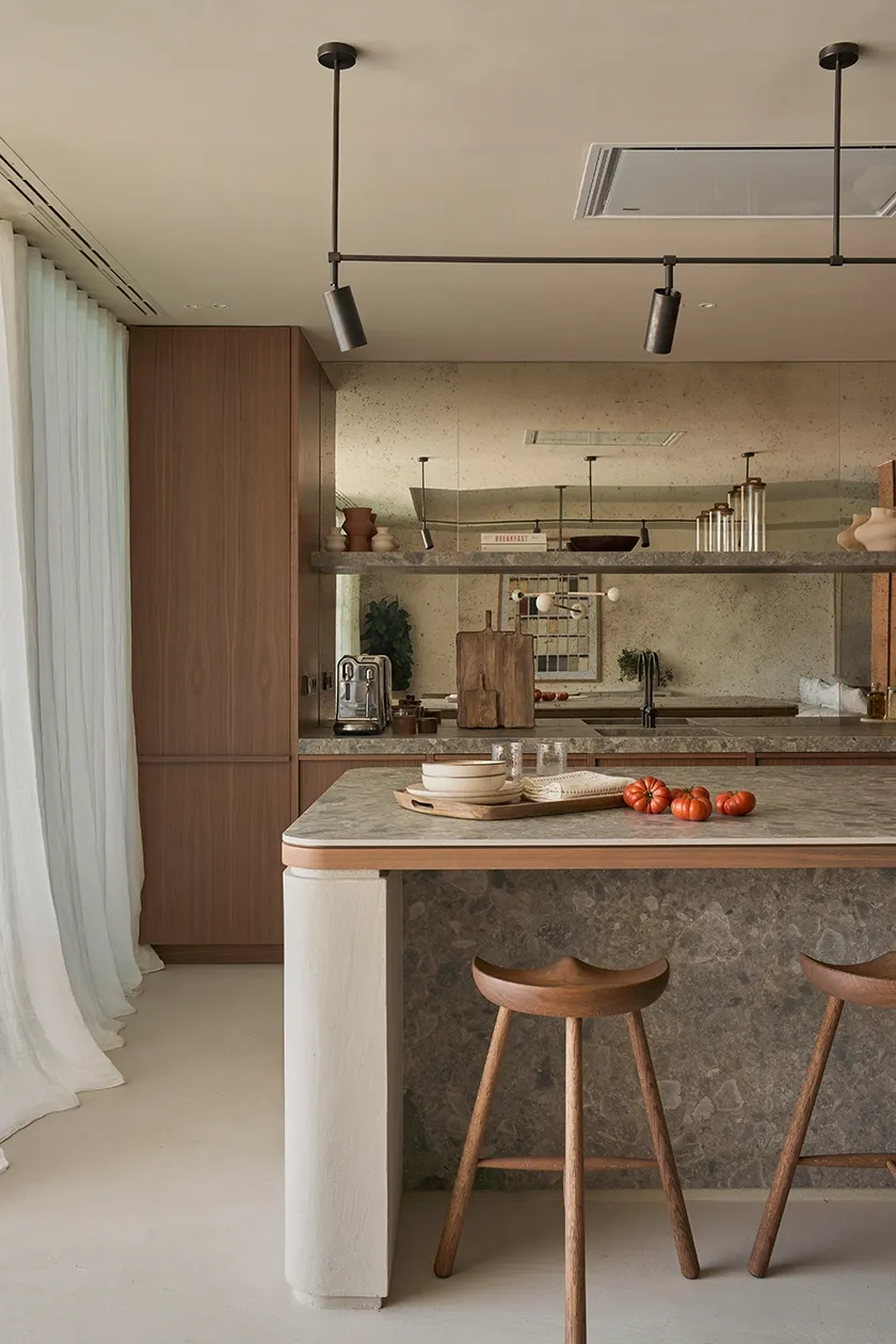 Luxury Ibiza kitchen interior with stone island, warm wood cabinets, and bar stools in Mediterranean style