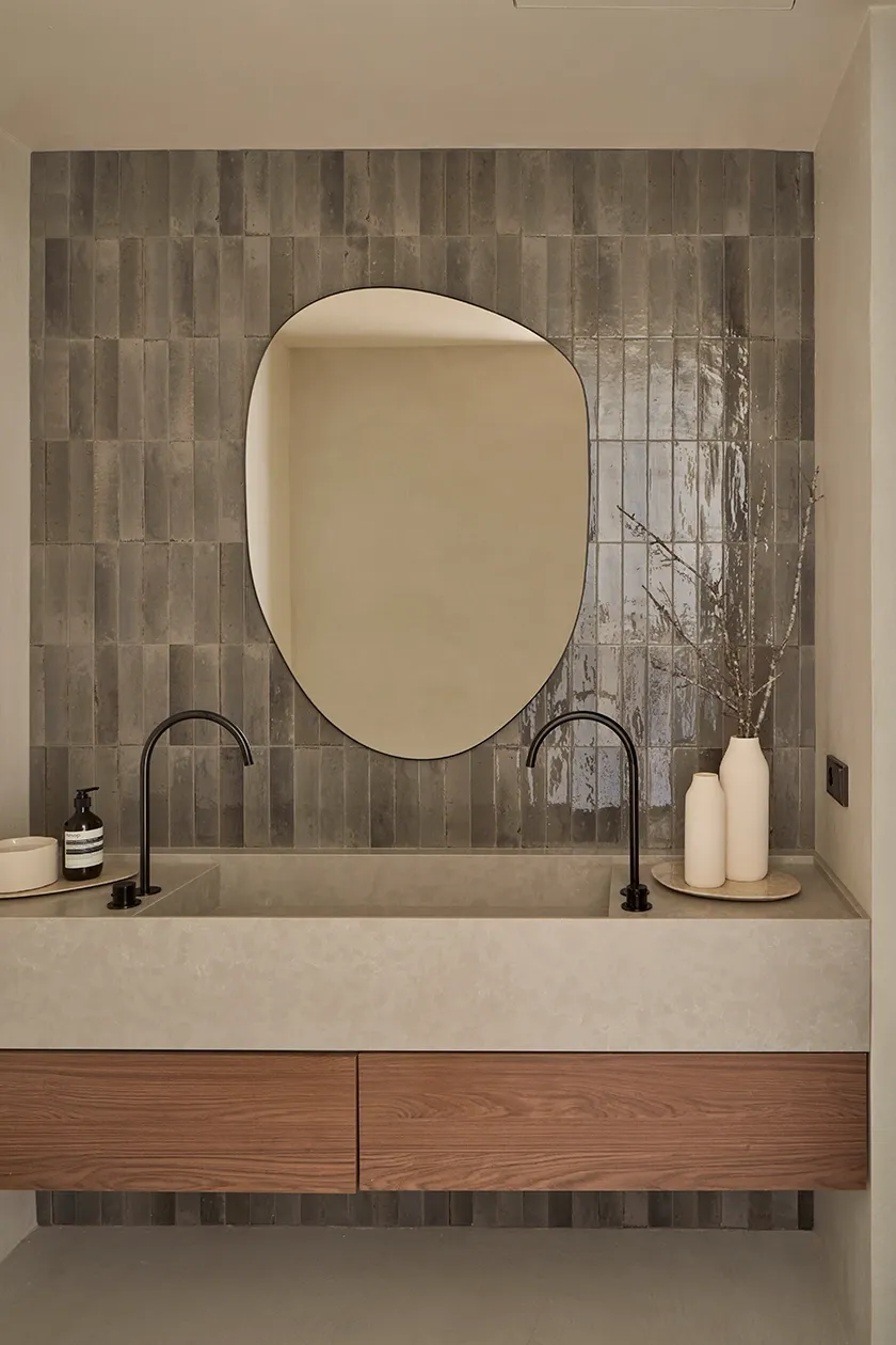 Contemporary bathroom with stone vanity, asymmetric mirror, and minimalist black fixtures in Mediterranean style