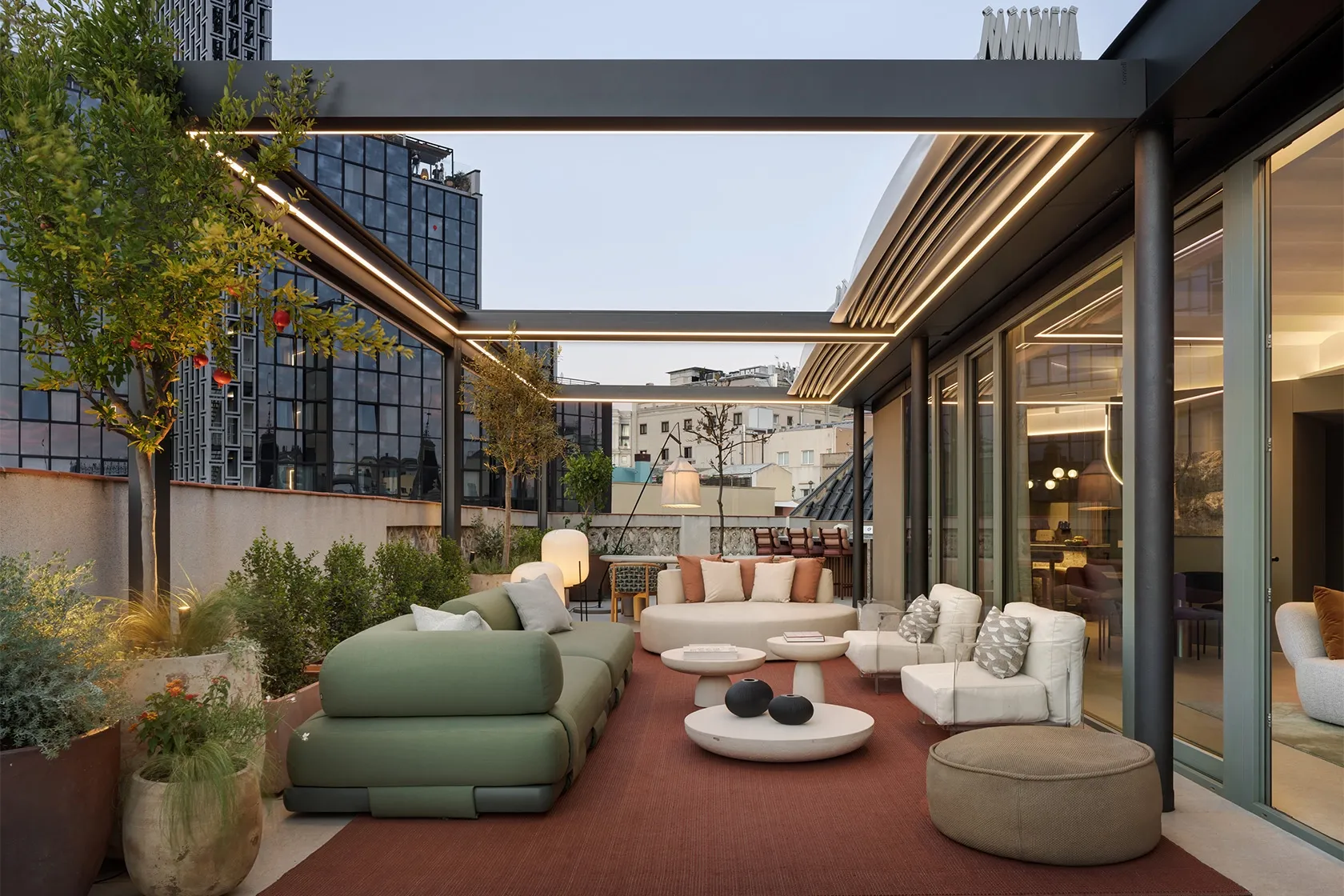 Rooftop terrace at dusk with modular lounge seating, integrated LED pergola lighting and low stone coffee tables.