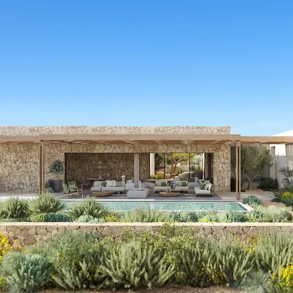 Frontal view of a luxury villa with white sculptural volumes, coastal vegetation, and ocean backdrop.