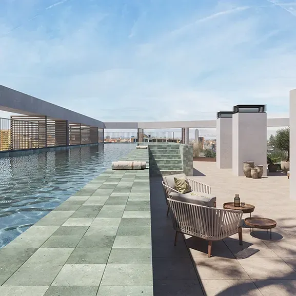 Rooftop pool with panoramic views of Barcelona, surrounded by natural stone finishes, modern loungers, and lush greenery in a serene urban oasis.
