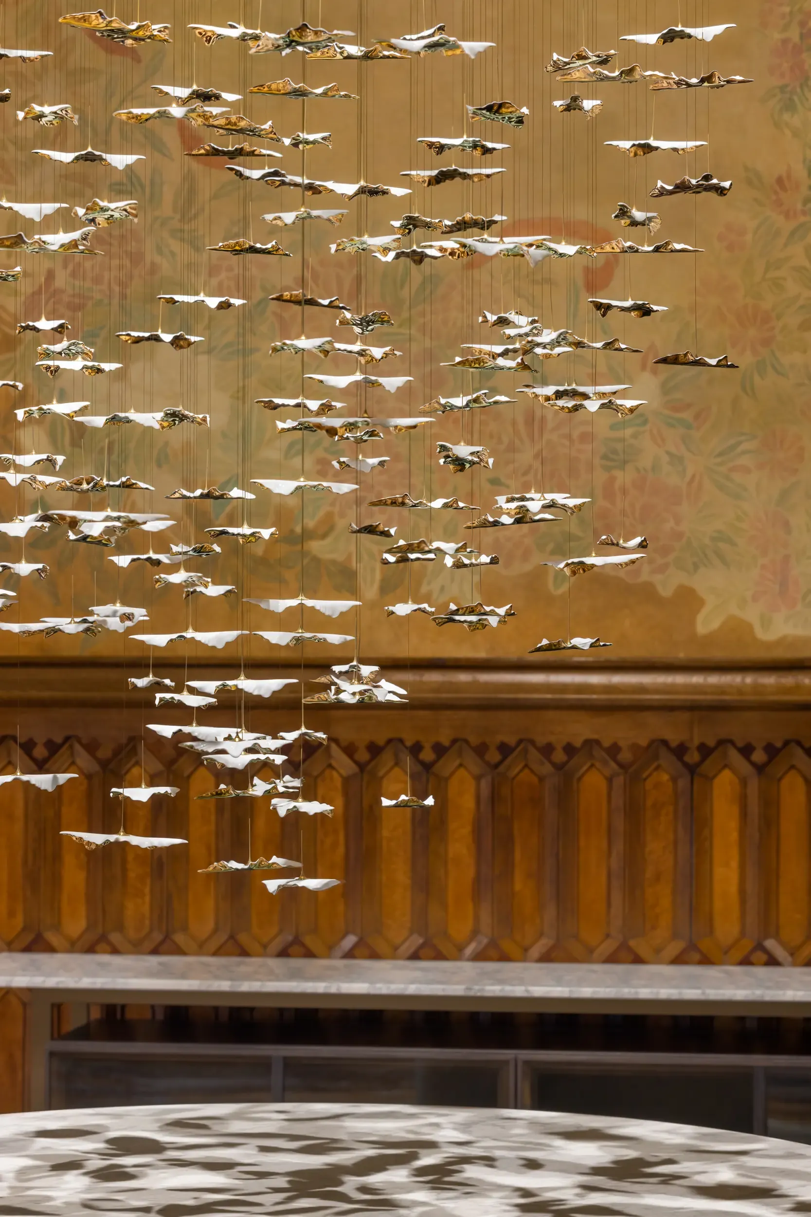 Close-up of hanging sculptural elements in metallic finish, part of an artistic ceiling installation.
