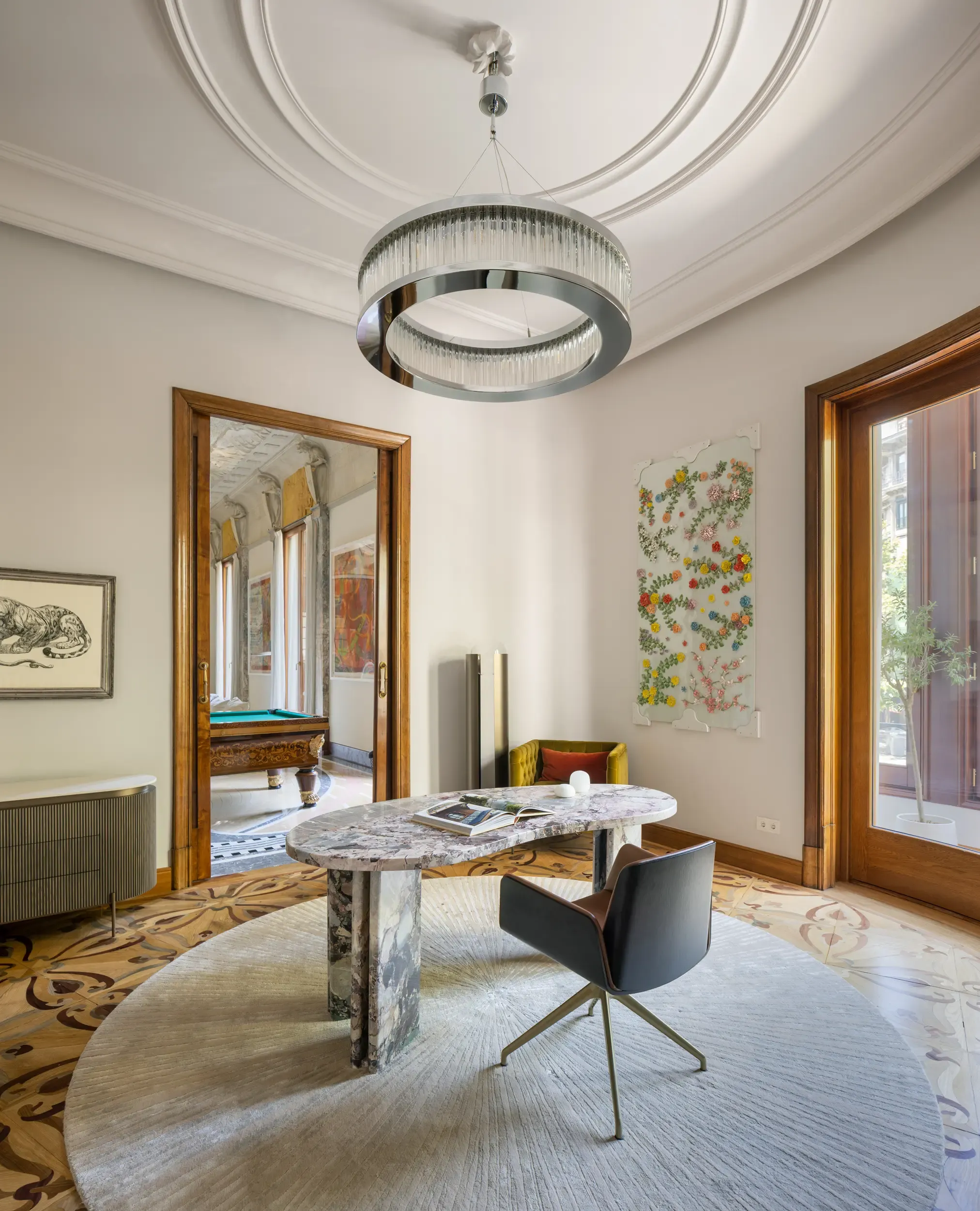 Stylish study with marble desk, designer lighting, and view into adjoining room with billiard table.
