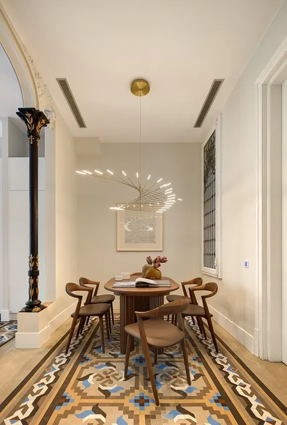 Dining area with hydraulic mosaic floor, sculptural light and restored columns by LUV Studio.