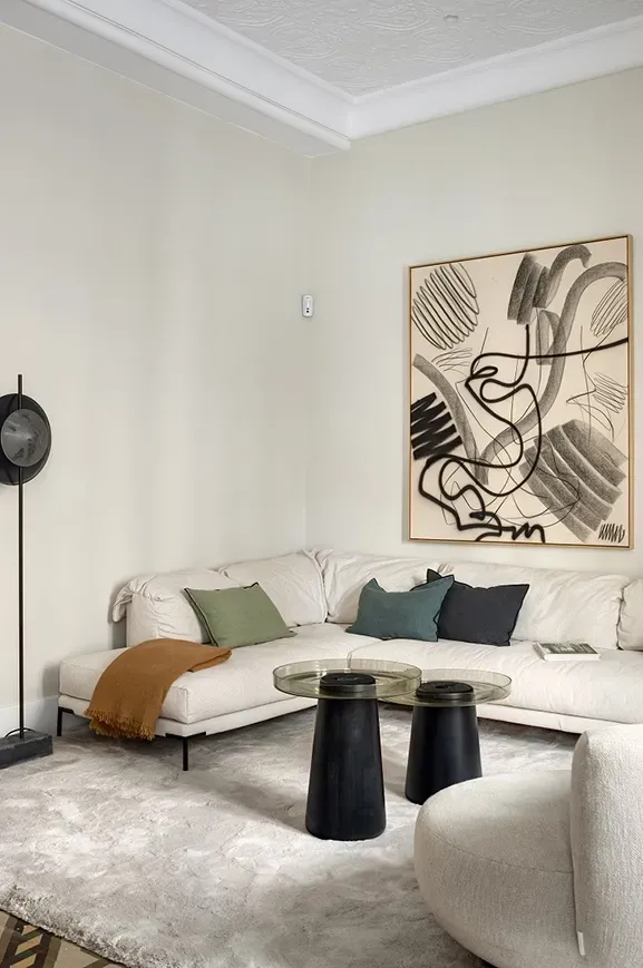 Contemporary living room in Casa Oller with cream sofa, graphic art and minimalist decor by LUV Studio.