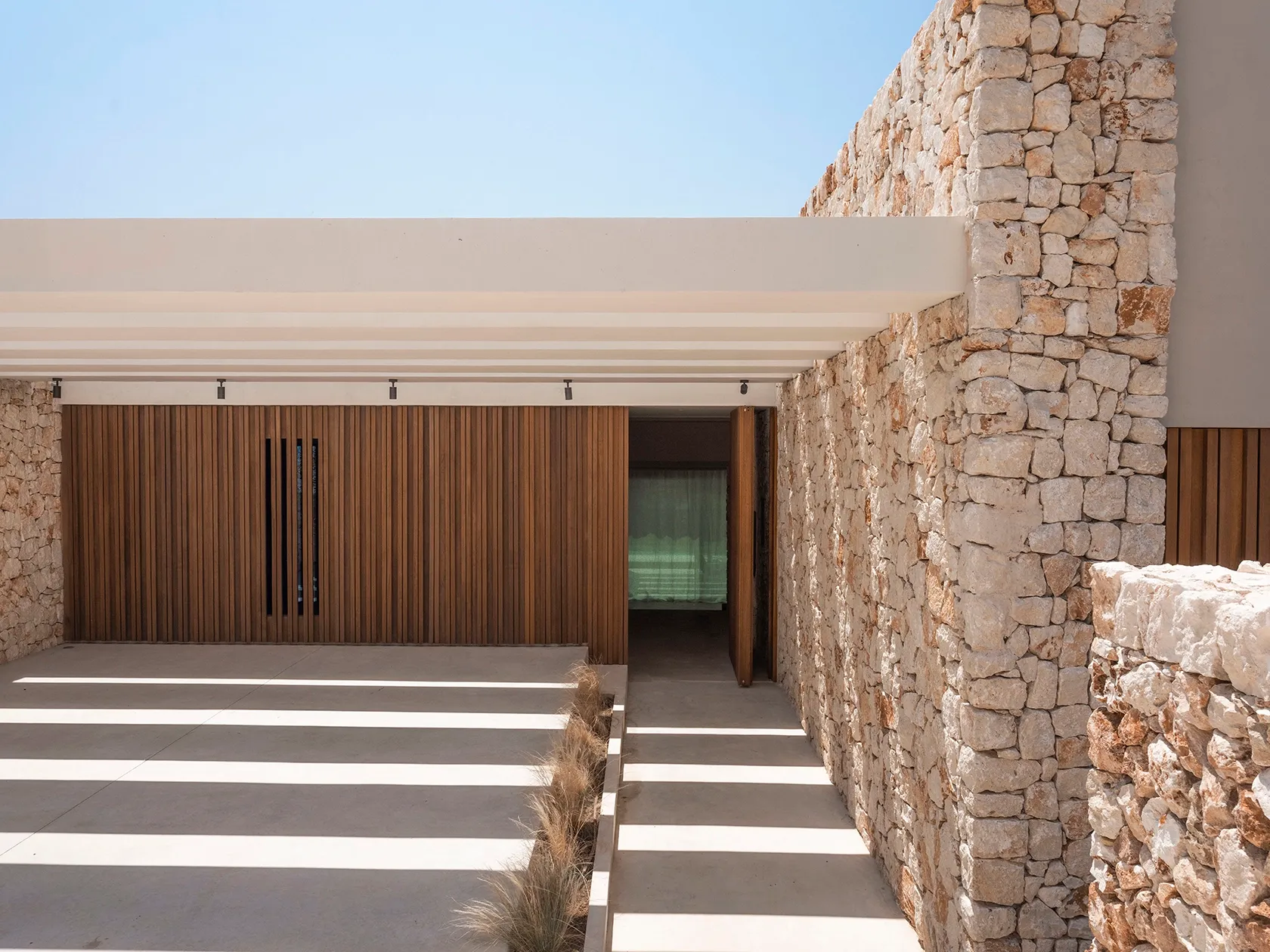 A welcoming entrance framed by stone, wood, and a light pergola.