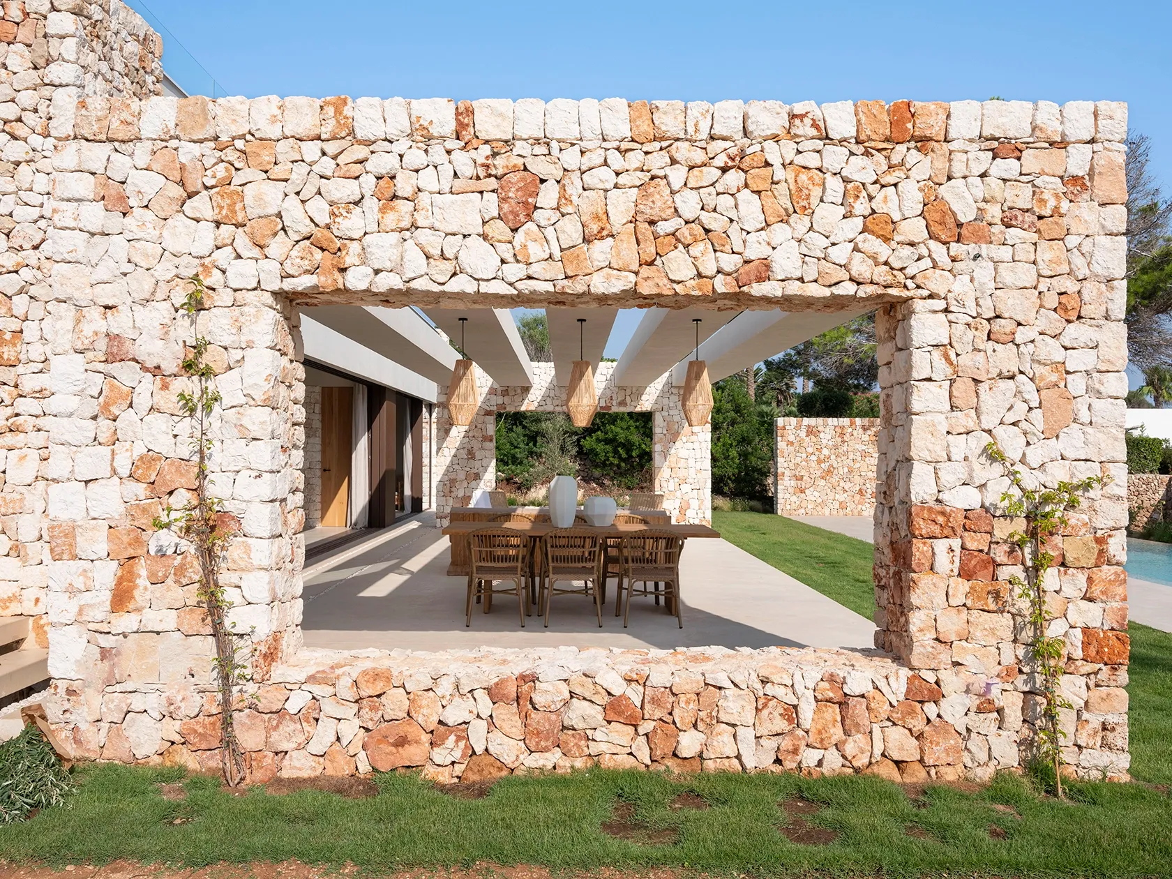 A stone wall anchoring the pergola with Mediterranean character.