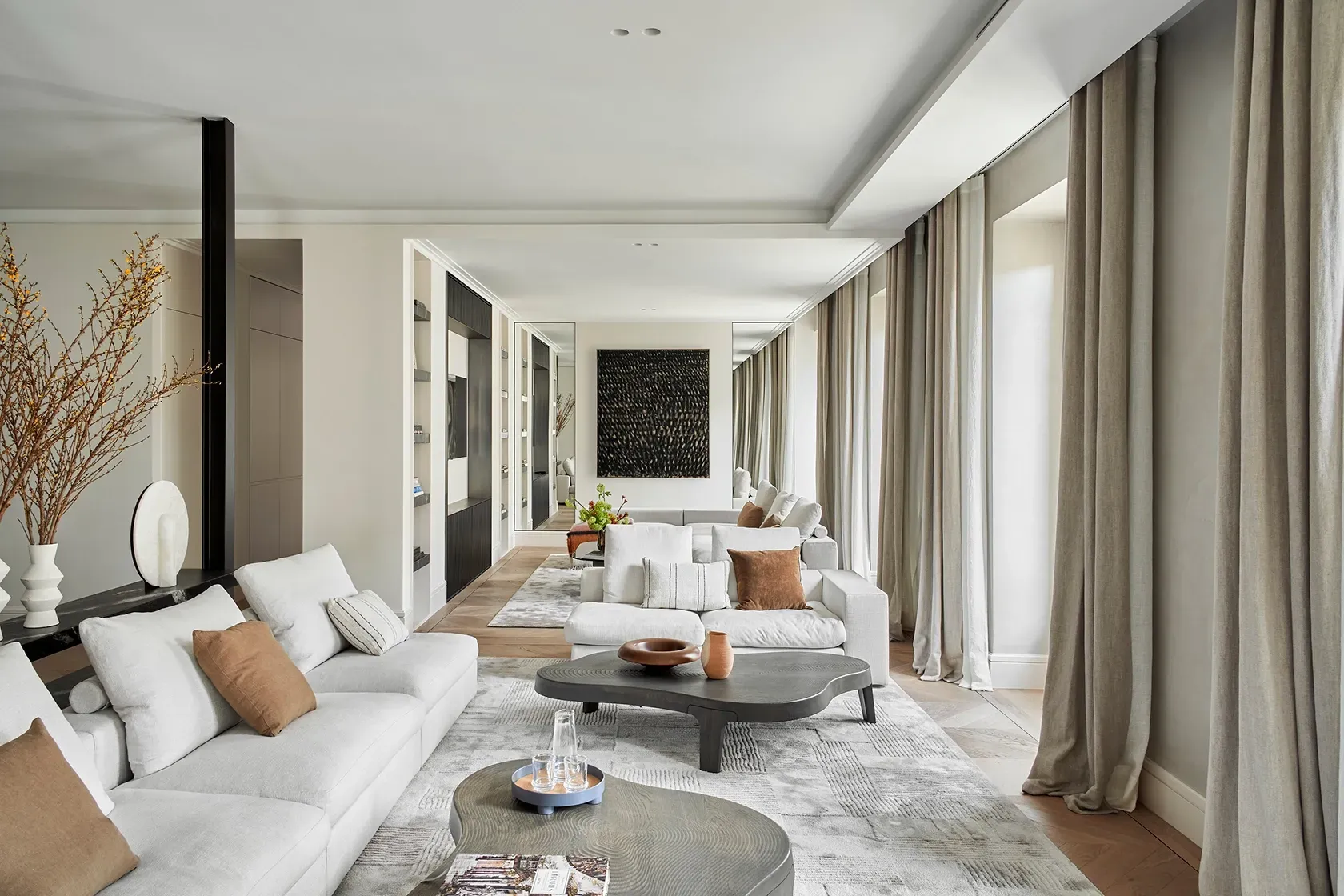 Sophisticated open-concept living room with modular seating, organic-shaped coffee tables, and layered decor in natural hues and luxurious textures.
