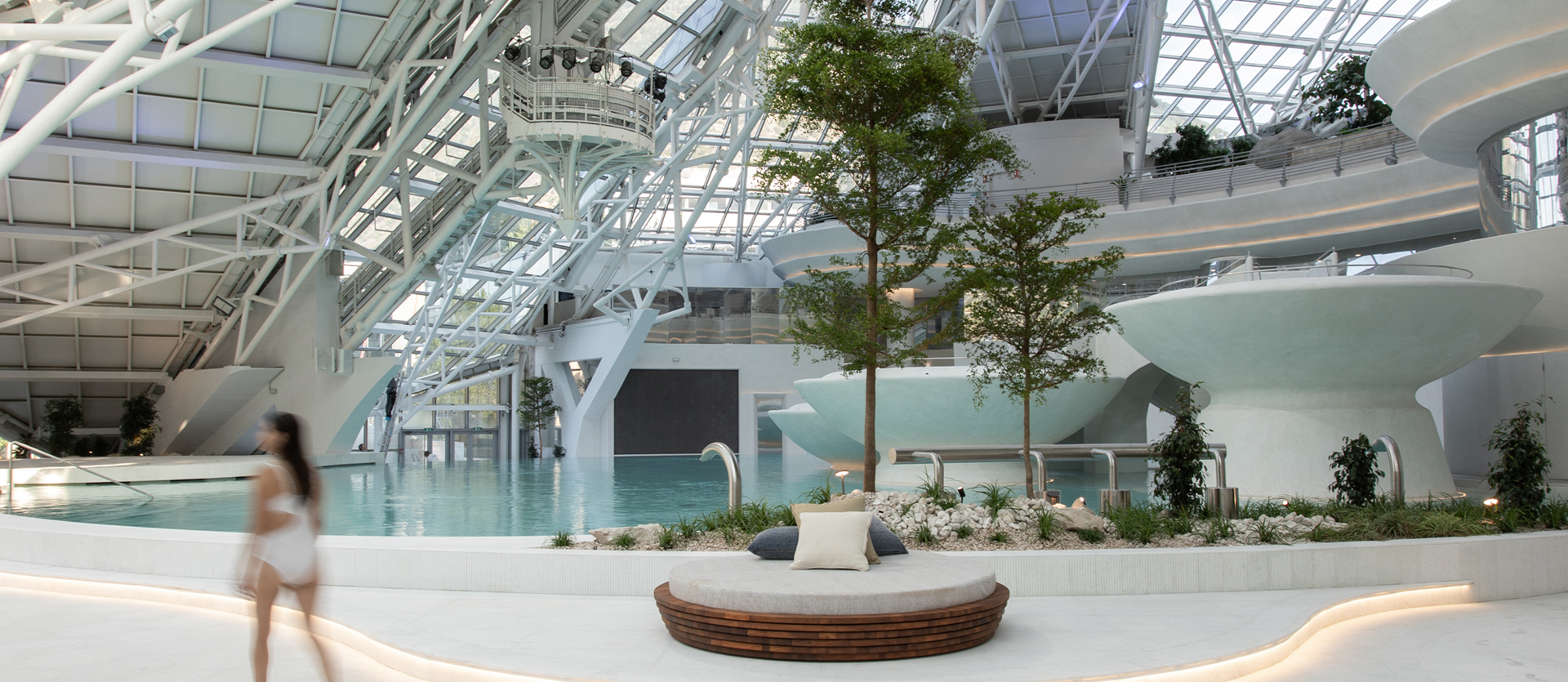 Panoramic view of spa interiors with thermal pools, sculptural columns, and soft ambient lighting. ￼
