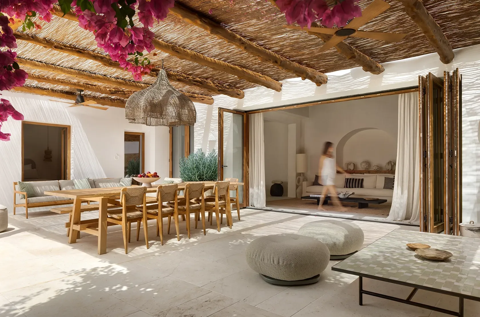 Rustic outdoor dining area with natural wood beams and vibrant bougainvillea, blending luxury and Mediterranean architecture.