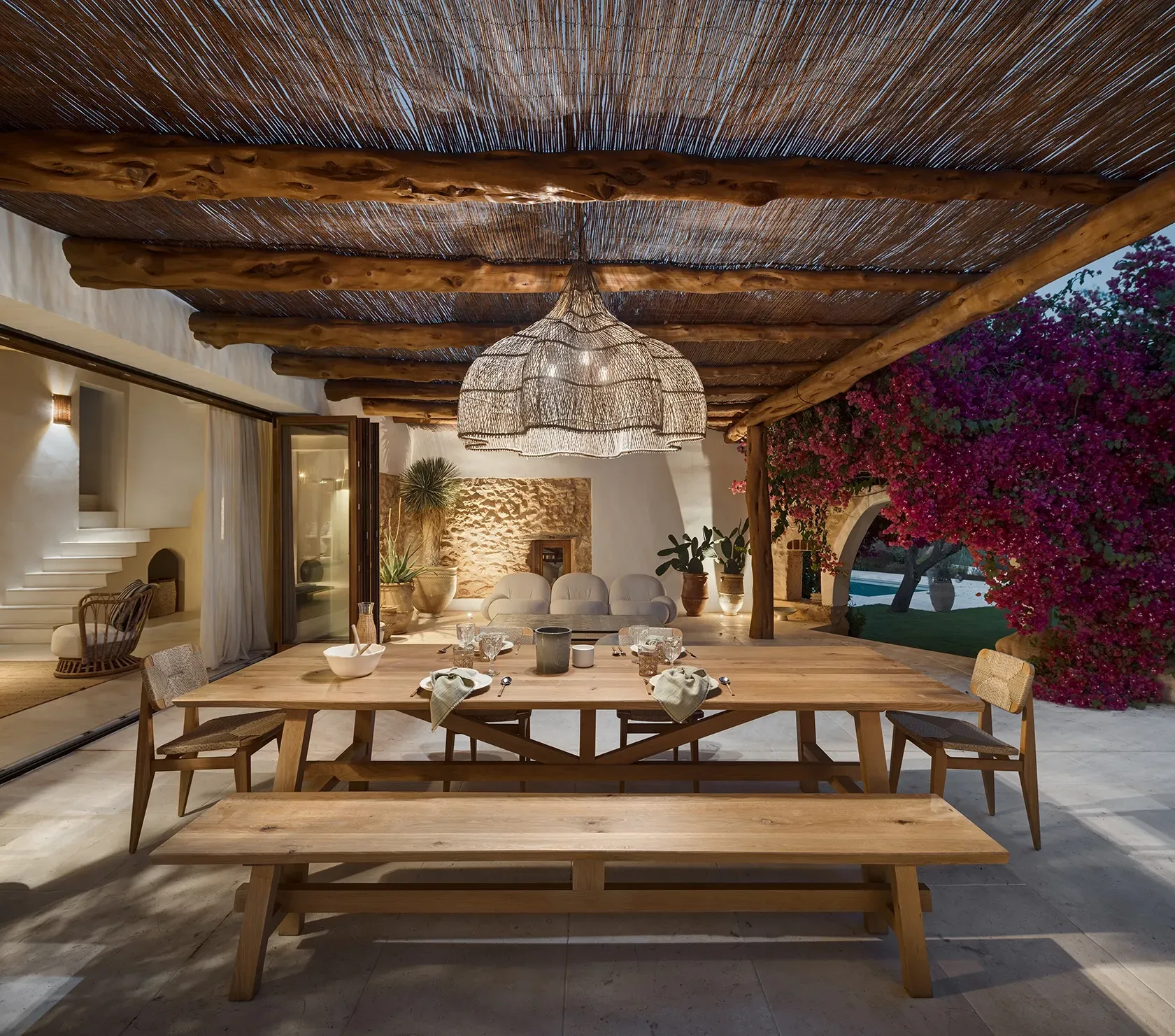 Nighttime terrace view with ambient lighting, rustic pergola, and bougainvillea, blending Mediterranean charm and luxury living.