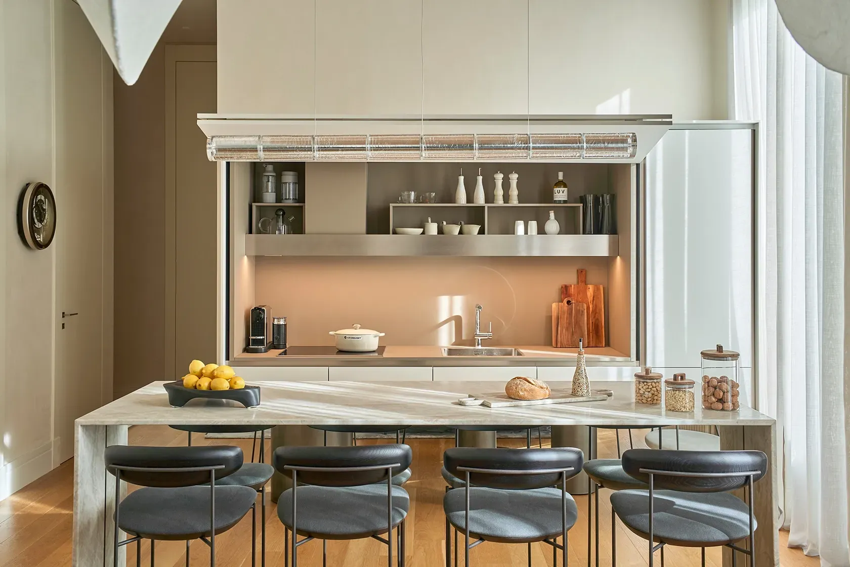 Vertical angle of a light-filled kitchen corner, showcasing refined surfaces, a textured backsplash, and built-in storage.