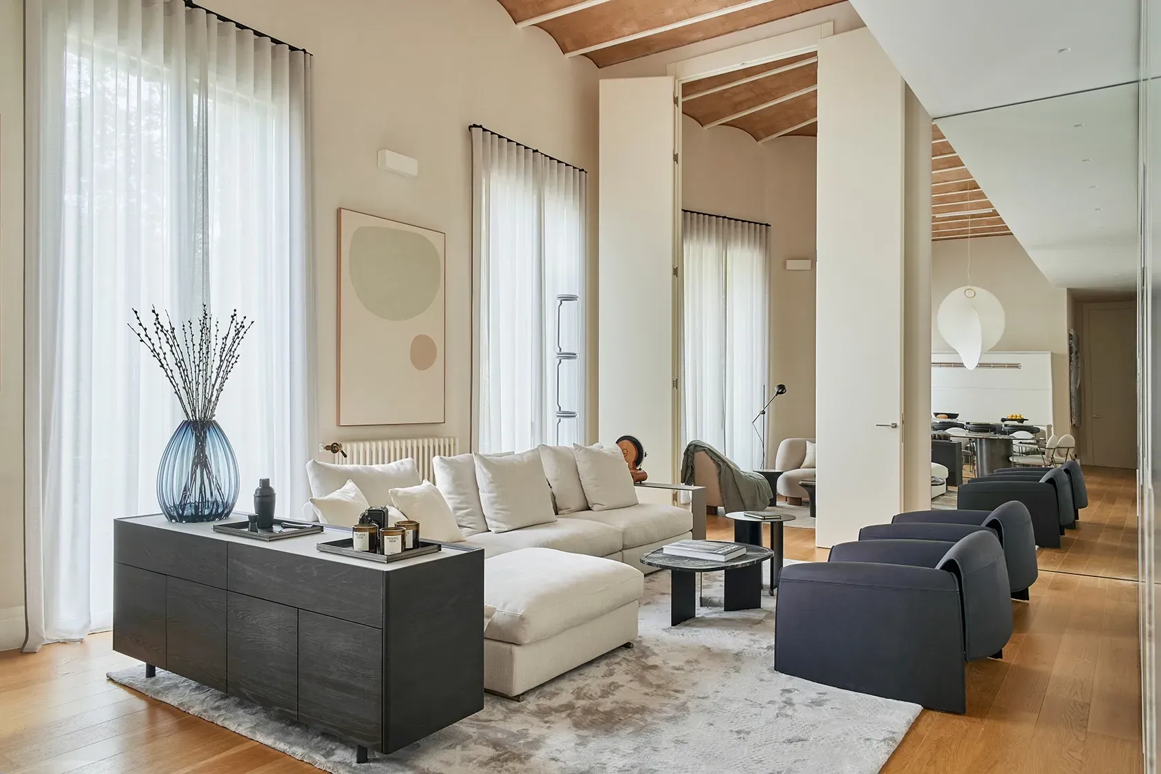 Contemporary living space with neutral tones, layered textures, and large windows that invite natural light.