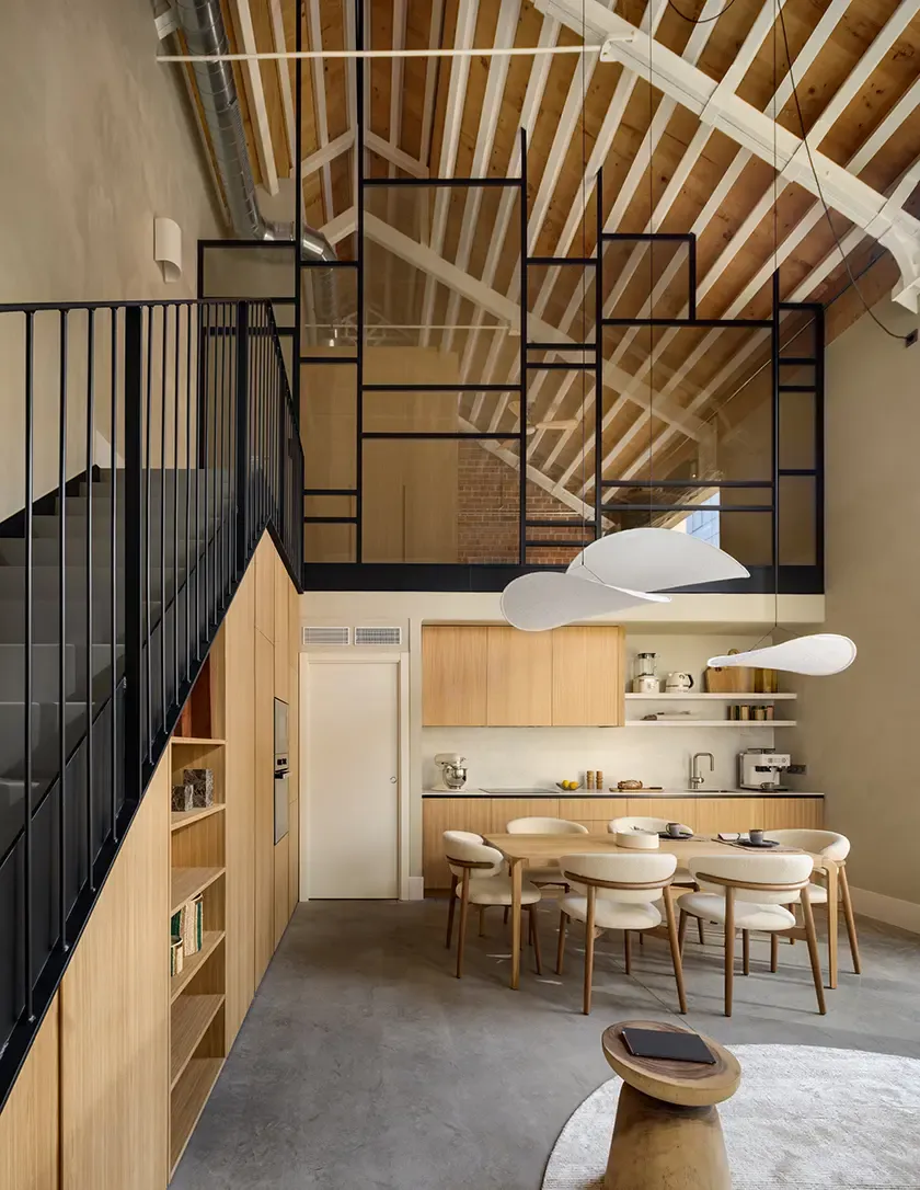 Double-height dining area with natural wood kitchen and contemporary loft interior design in Can Ricart