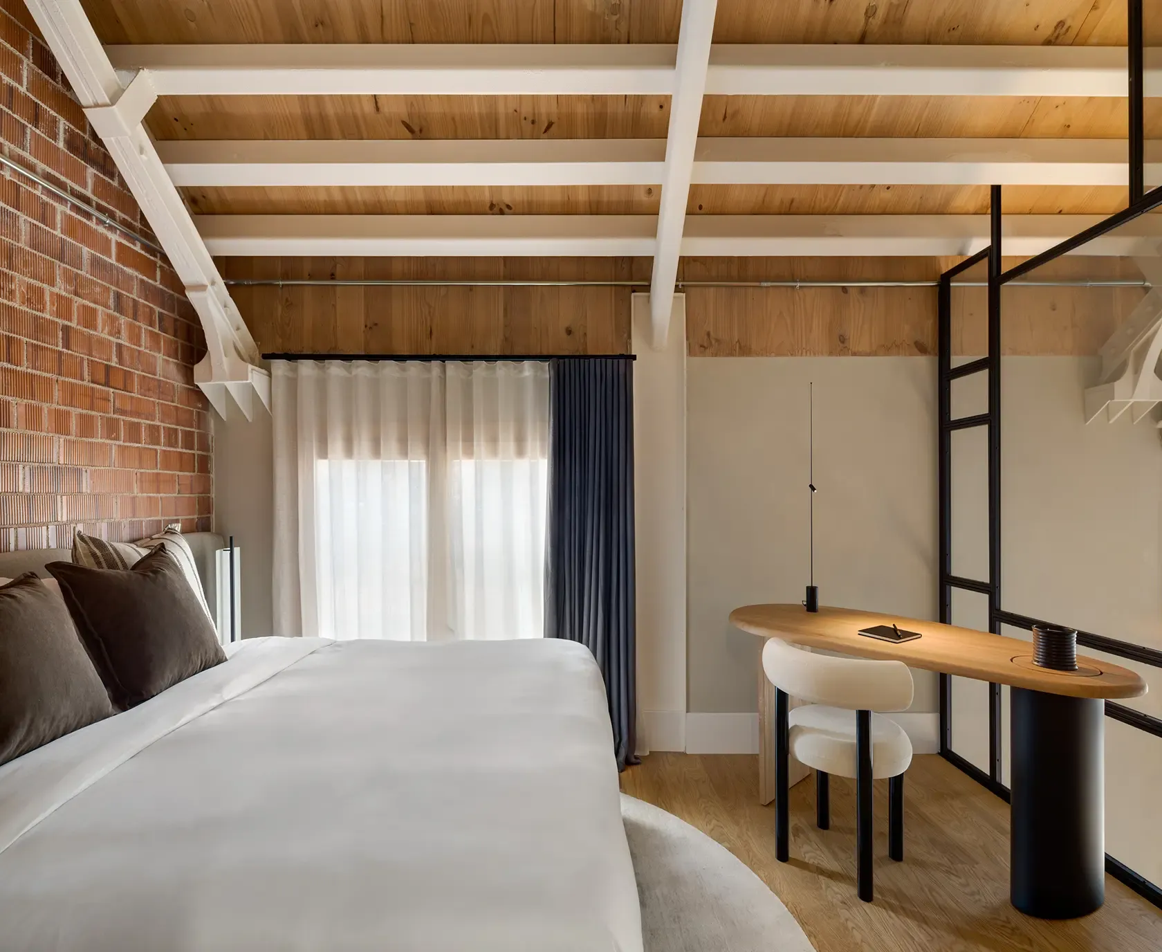 Master bedroom with exposed brick wall and integrated workspace in modern loft