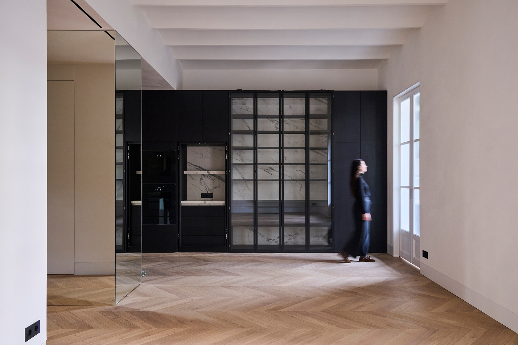Living space with custom cabinetry, glass display units and natural light entering through tall windows