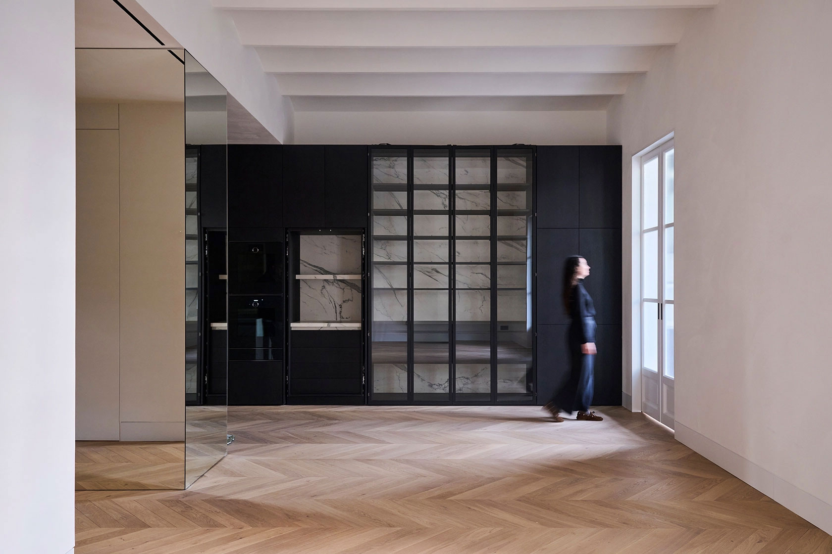 Living area with custom cabinetry, glass display units and natural light entering through tall windows