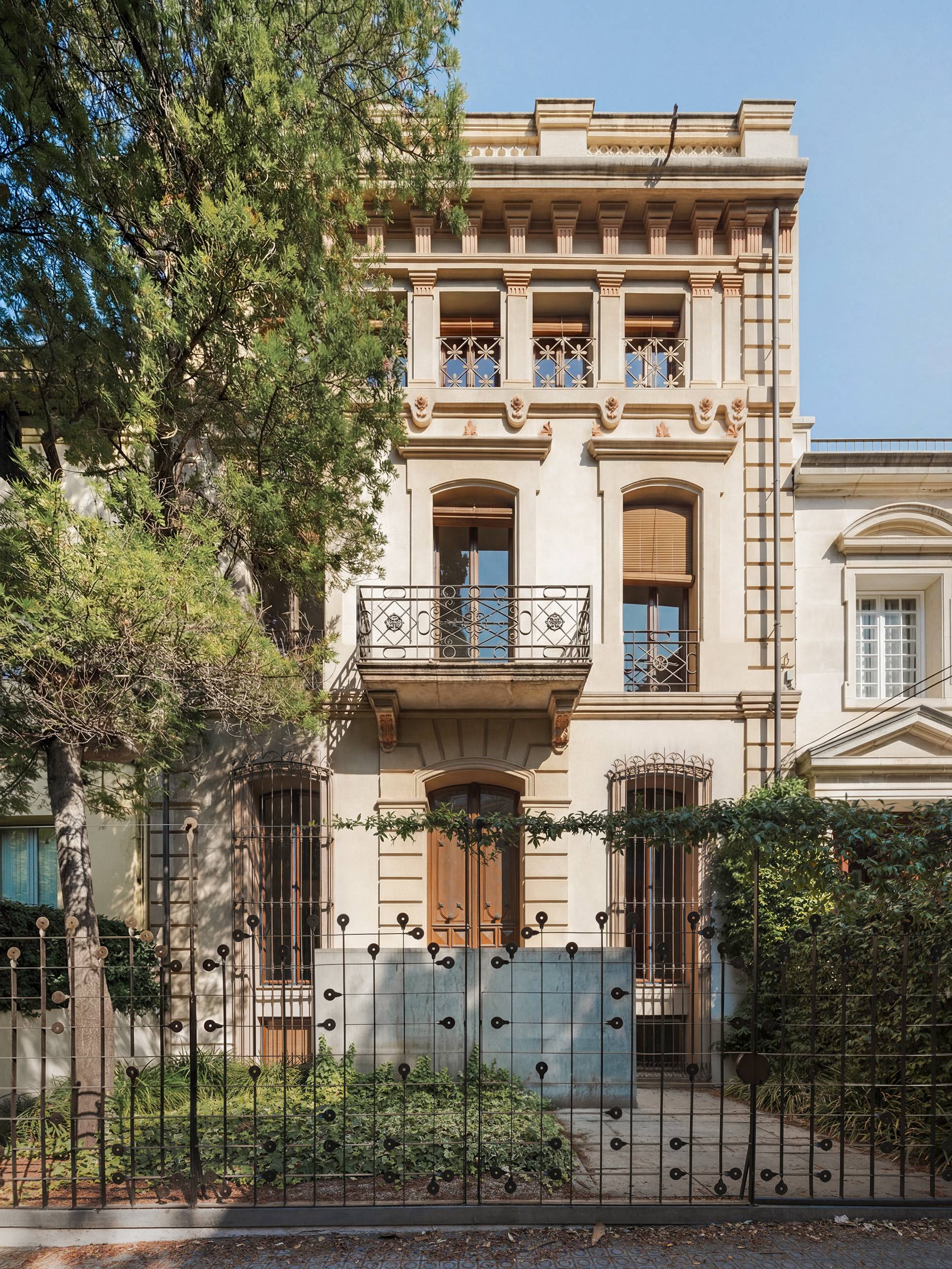 Historic residential facade with classical detailing, wrought iron balconies and landscaped front garden.