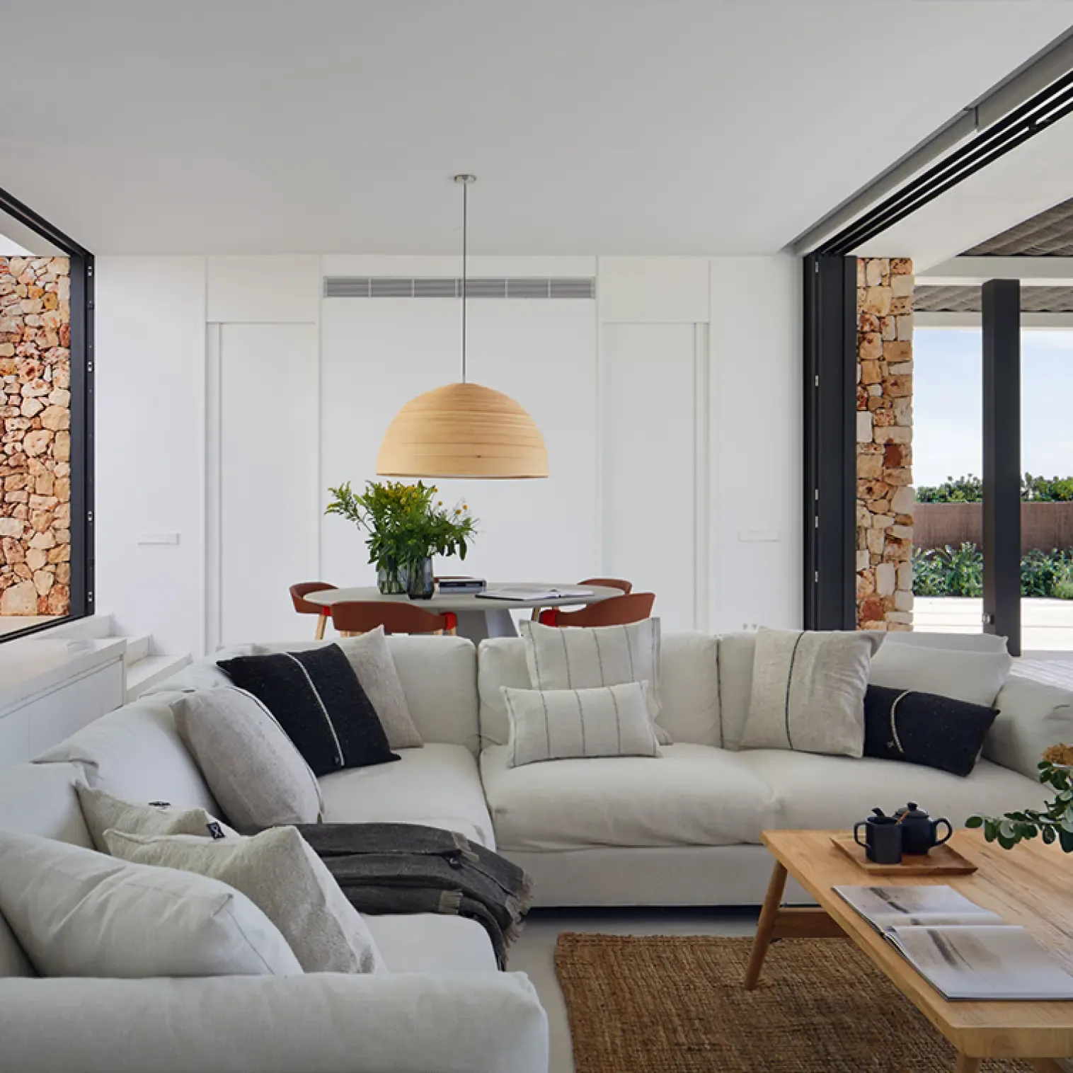 Interior living room with floor-to-ceiling windows, neutral-toned furniture, and cactus-filled patio views.