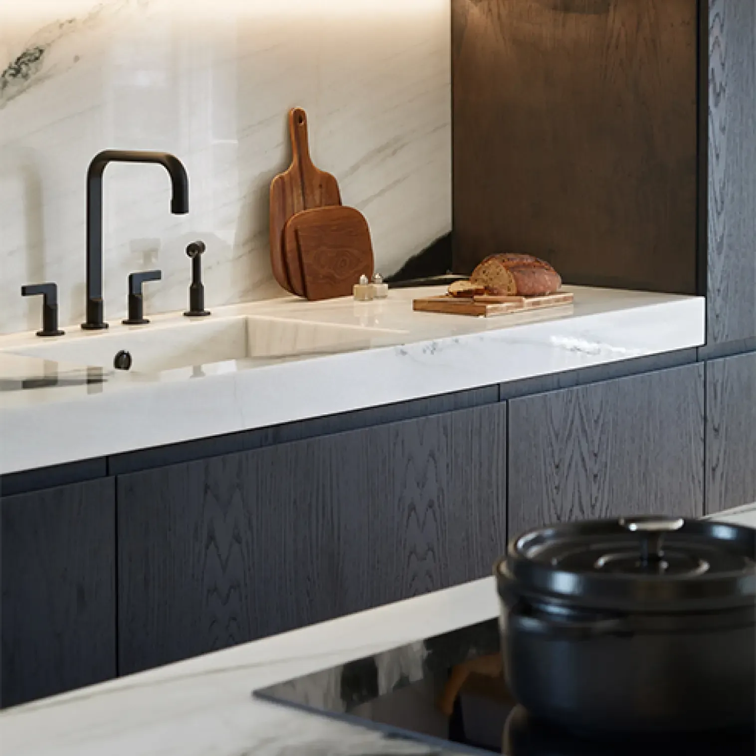 Close-up of marble kitchen counter with integrated sink, black fixtures, and wooden cutting board adding warmth to sleek modern design.