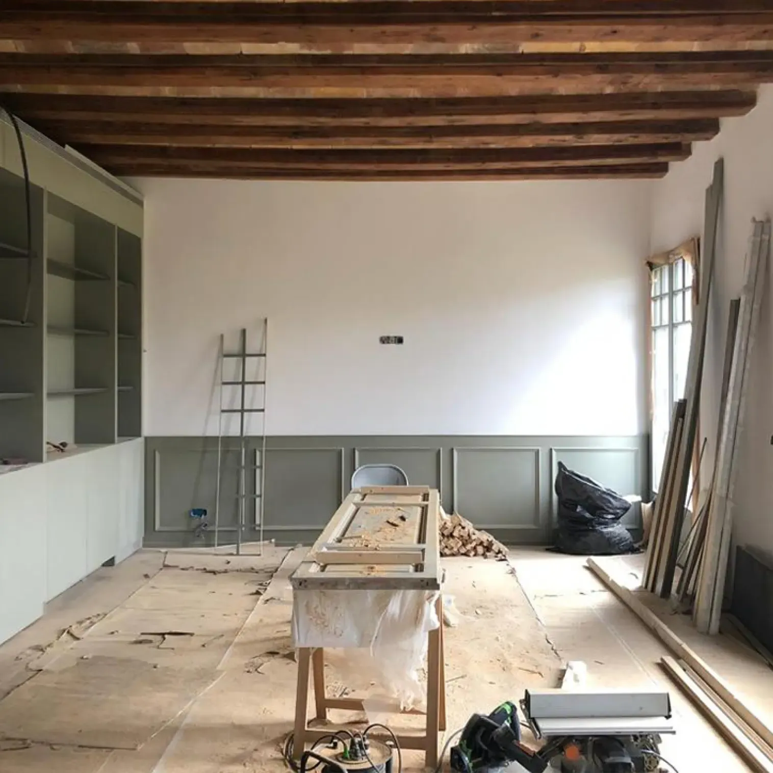 Office under construction with custom cabinetry, exposed beams, and classic window frames in Barcelona’s Eixample district.