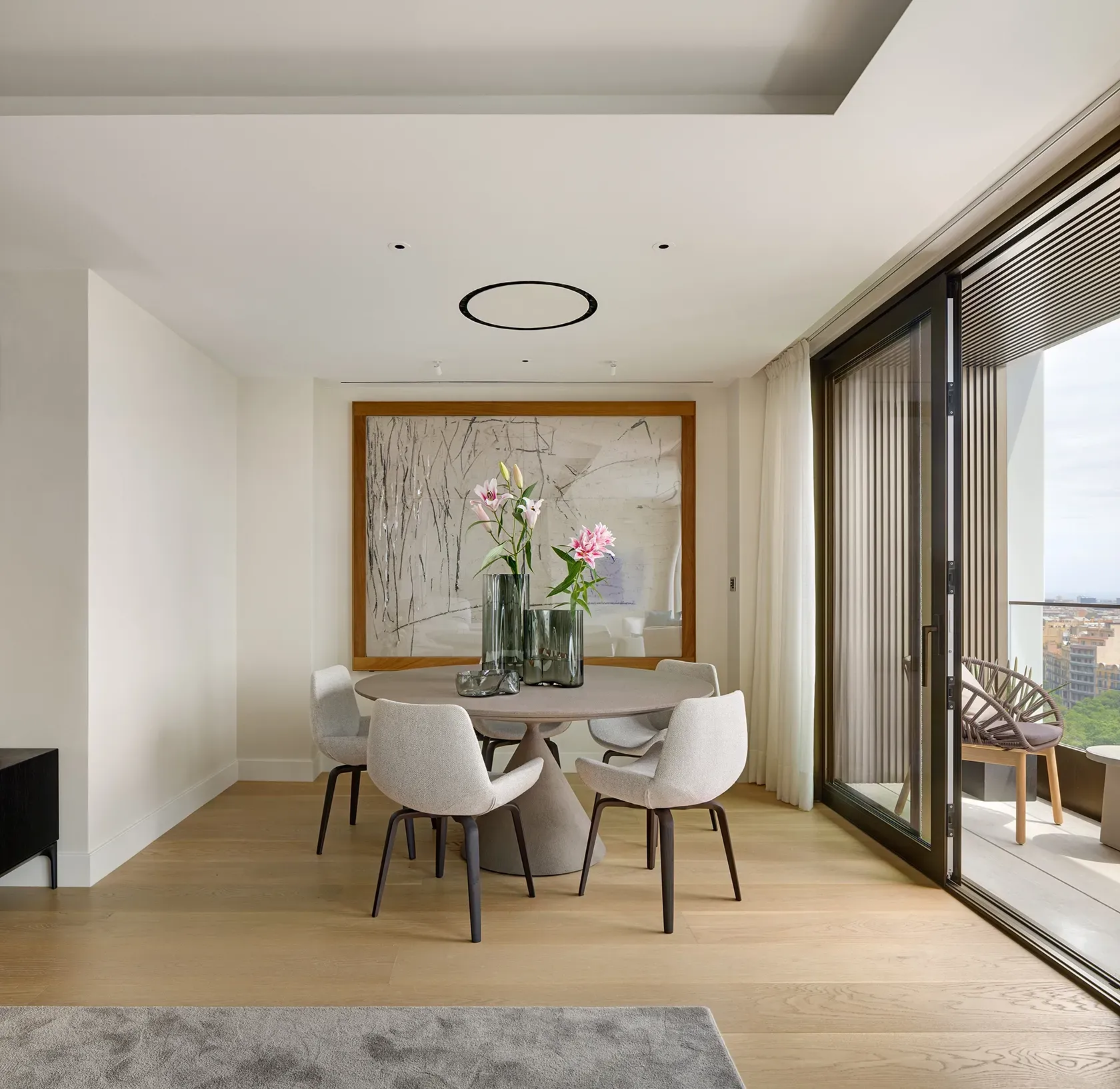 Modern dining space with sculptural table and floral centerpiece, opening to terrace at Mandarin Oriental Residences.