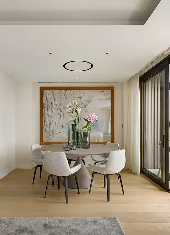 Modern dining space with sculptural table and floral centerpiece, opening to terrace at Mandarin Oriental Residences.